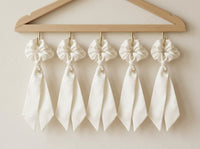 Gala ivory silk scrunchies displayed on oak wall hanger
