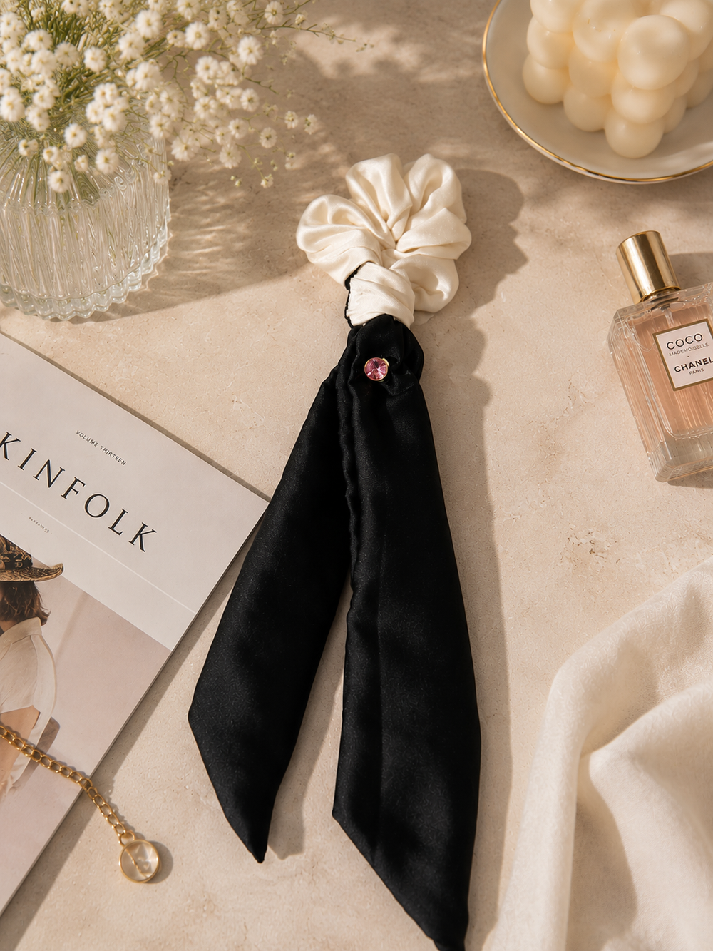Gala ivory silk scrunchie with black ribbon tails and pink crystal — flat lay