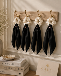 Gala ivory silk scrunchie collection displayed on brass hooks